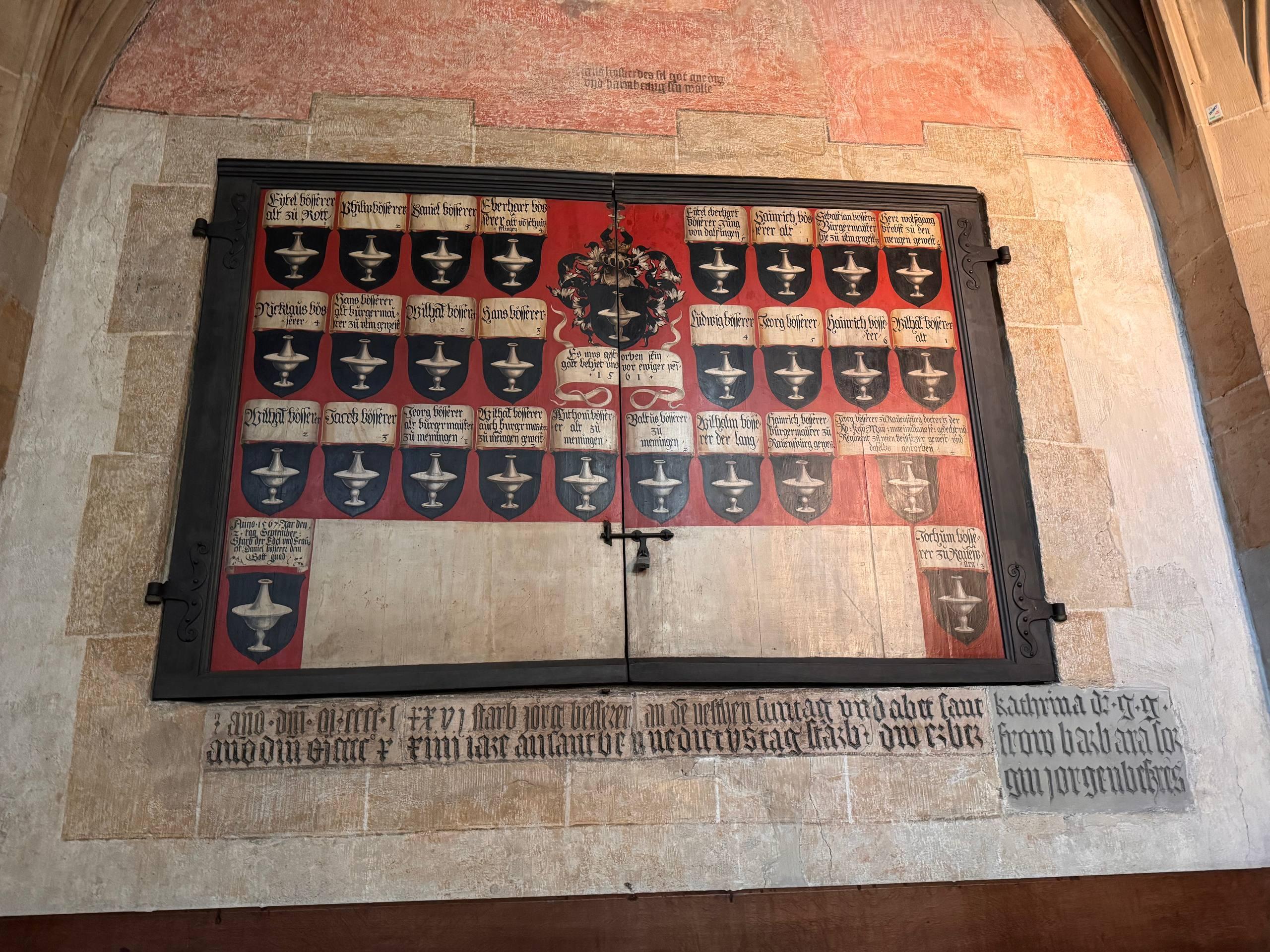 A large 16th-century painted memorial panel inside Ulm Minster, covered in small family shields and names of the Besserer family