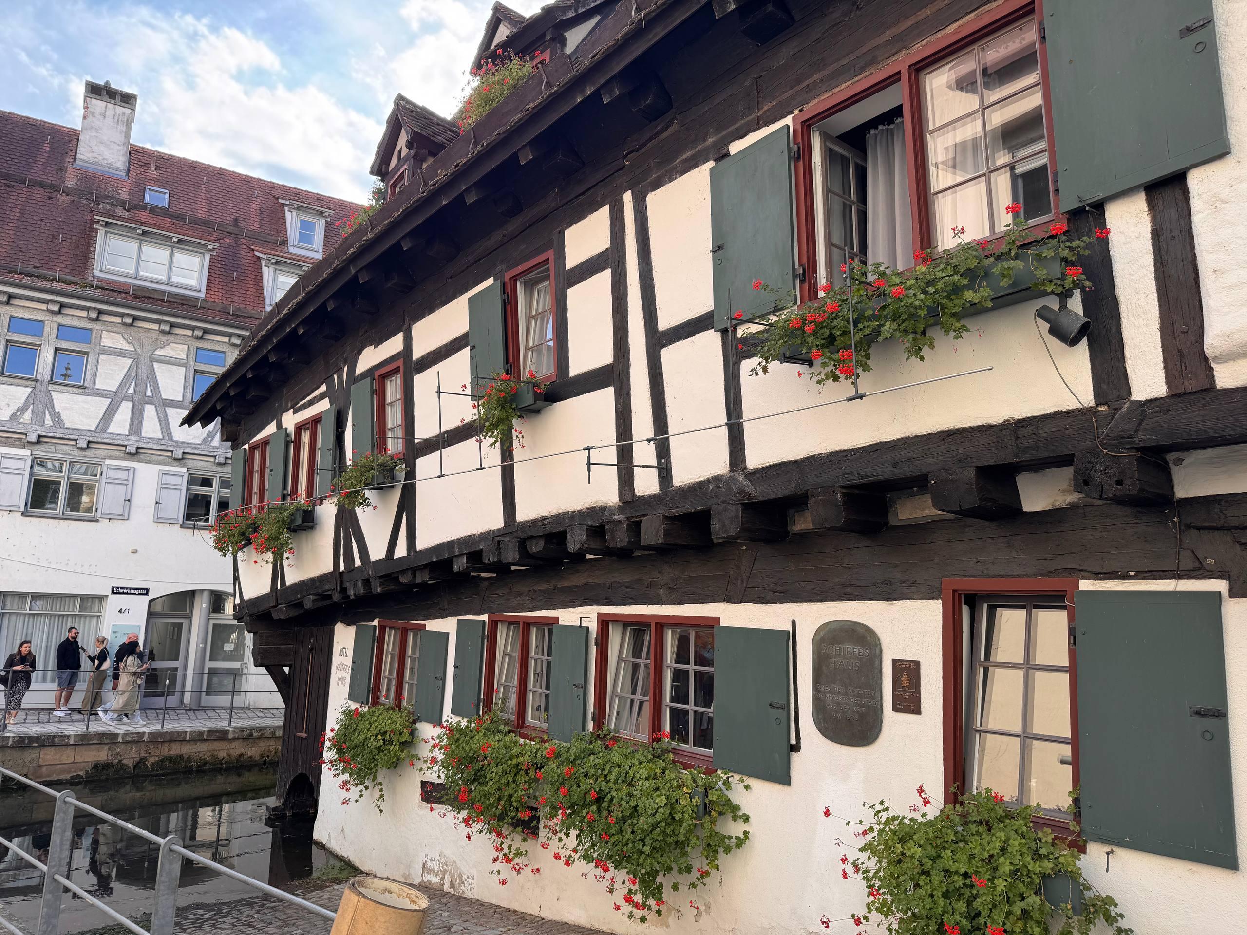 A wider view of the leaning Schiefes Haus hotel and the old town of Ulm along the canal