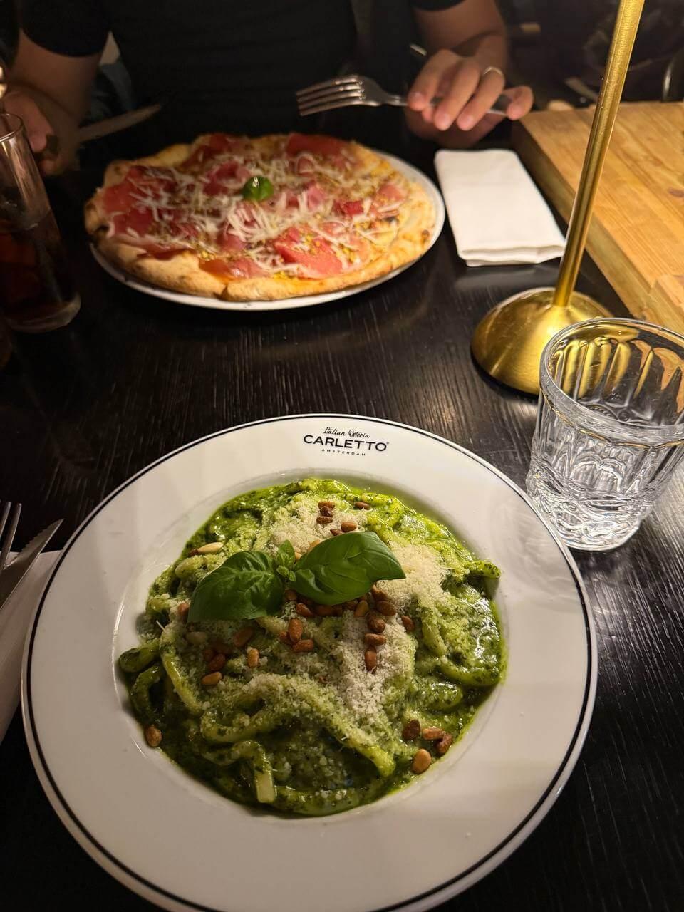 Pizza and pesto pasta on the table at Carletto, an Italian restaurant in Amsterdam