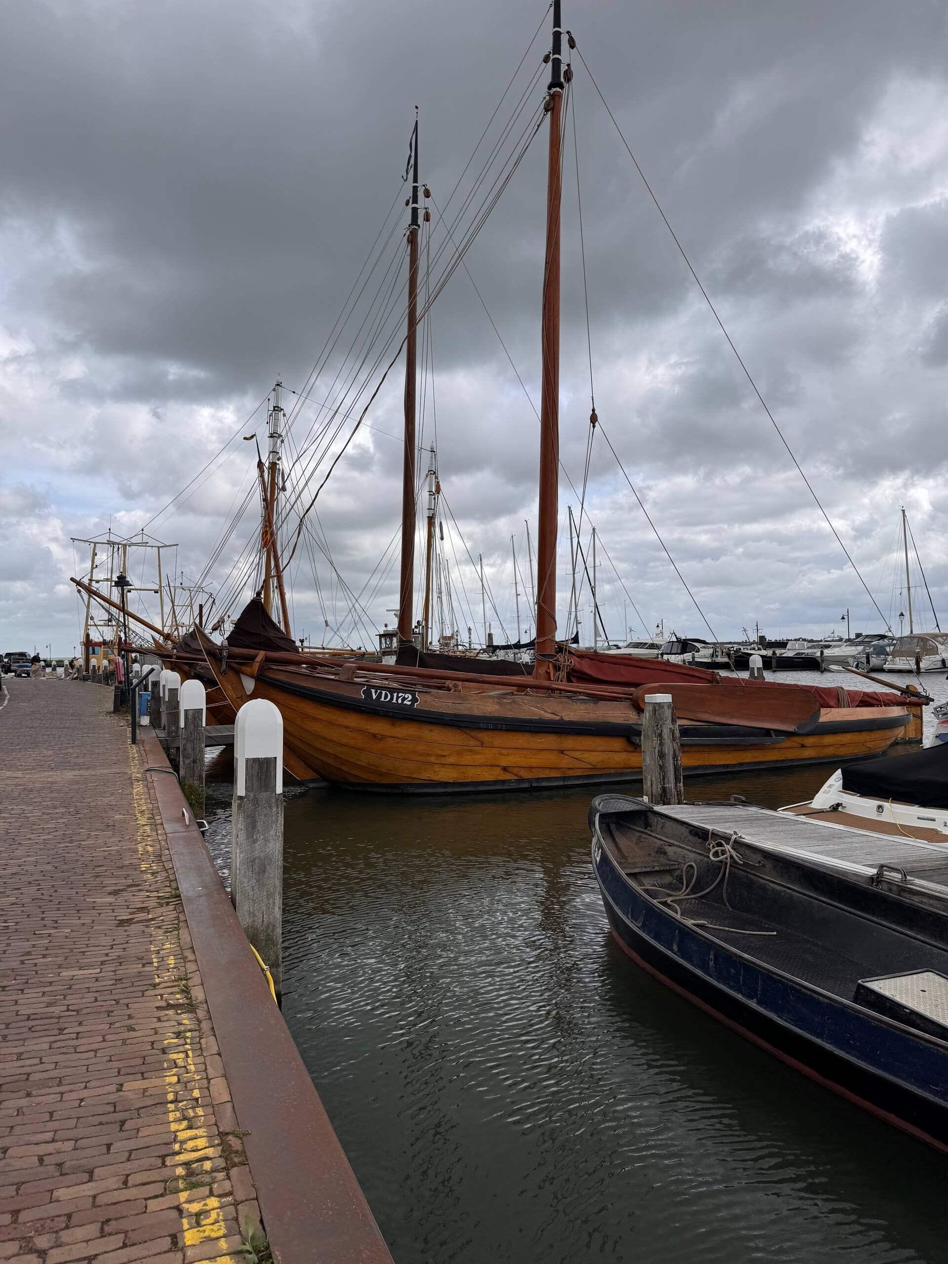 Traditional wooden sailing boats moored in Volendam's harbor under a cloudy sky