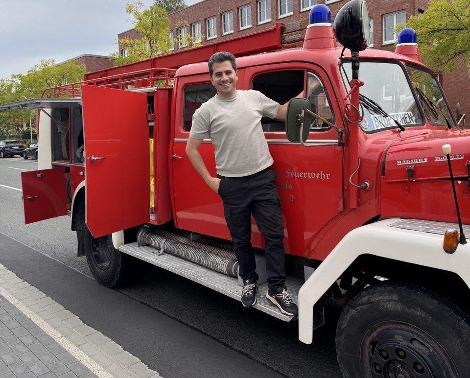 A colleague standing next to a restored vintage Magirus fire truck